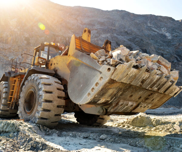 Wheel loader machine unloading rocks in the open-mine of iron ore